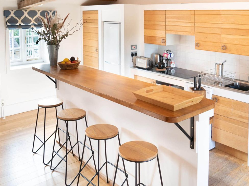 A kitchen with an island and bar stools at The Old Barn in Manchester