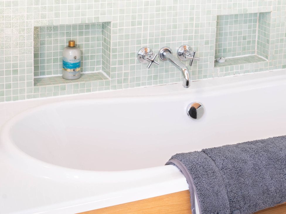 A bathtub with a gray towel and a shampoo bottle at The Old Barn in Manchester