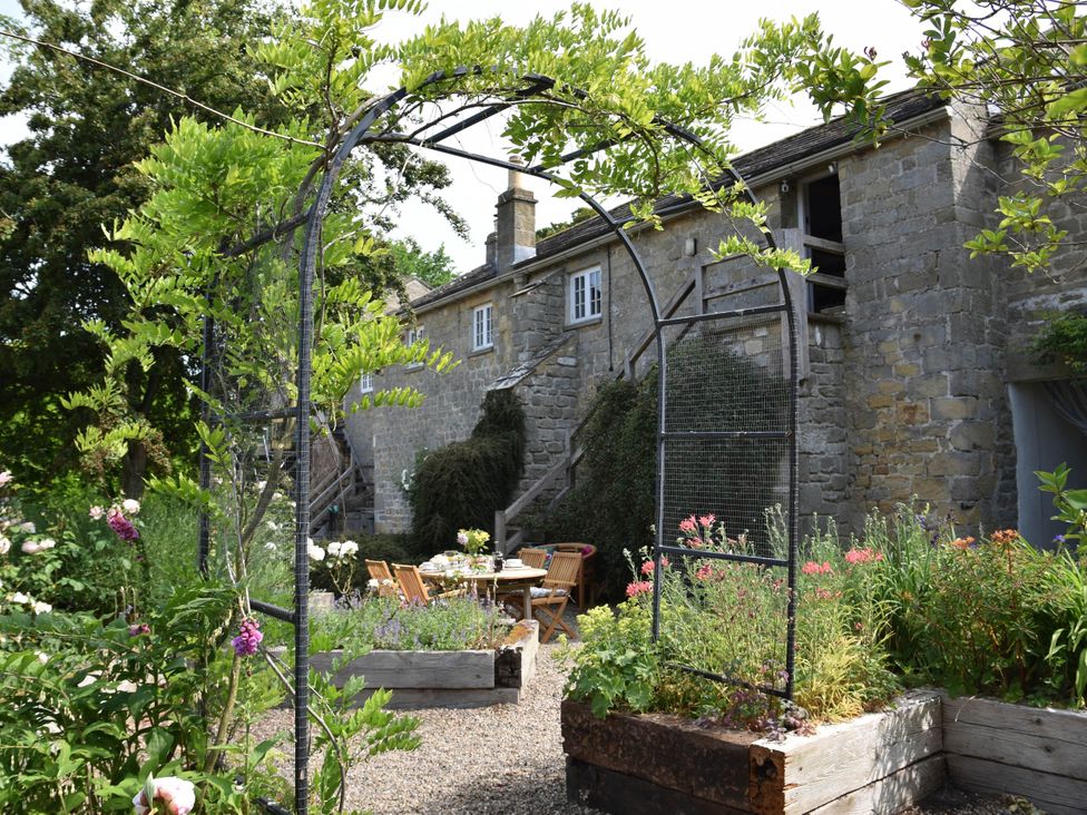 A garden with an archway, table and chairs at a property