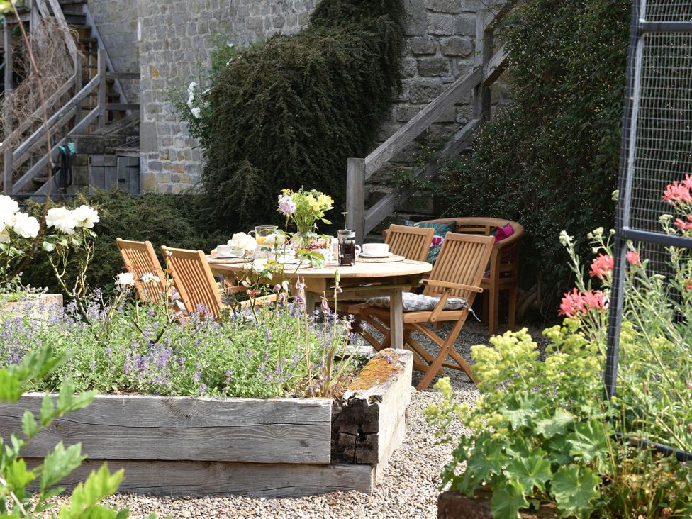 A garden with a table and chairs among flowers at 