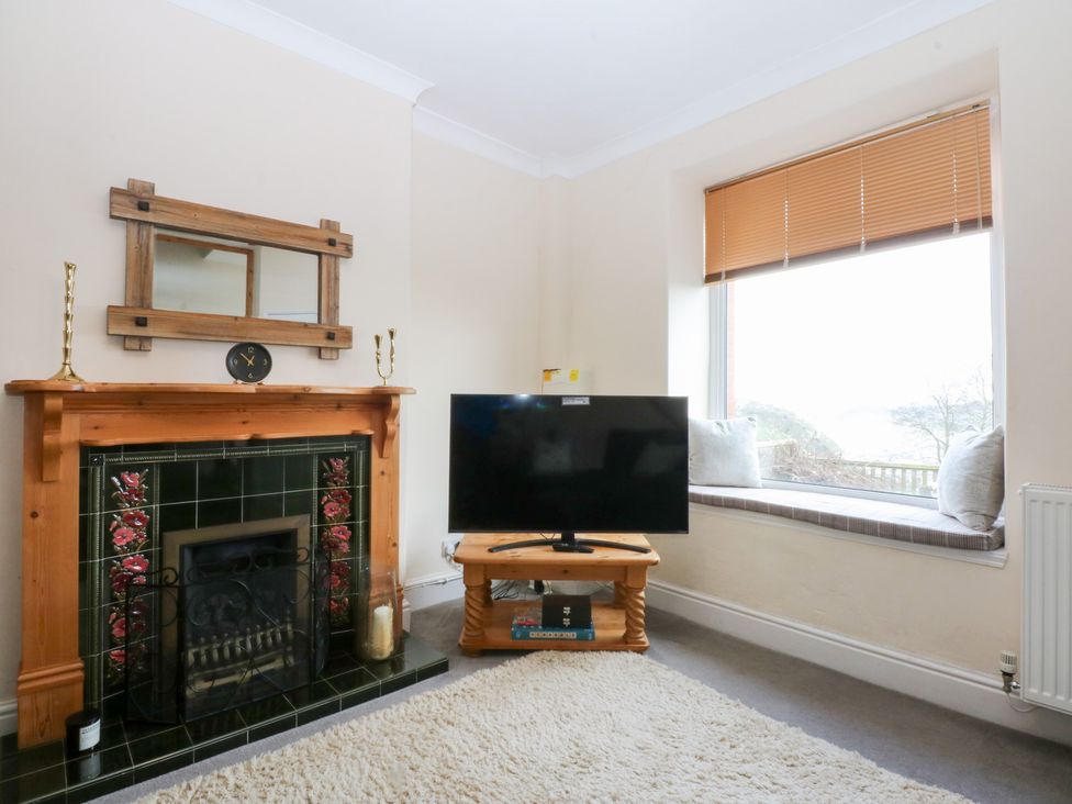 A living room with a fireplace and television at 3 Bay View Terrace in Llandegfan