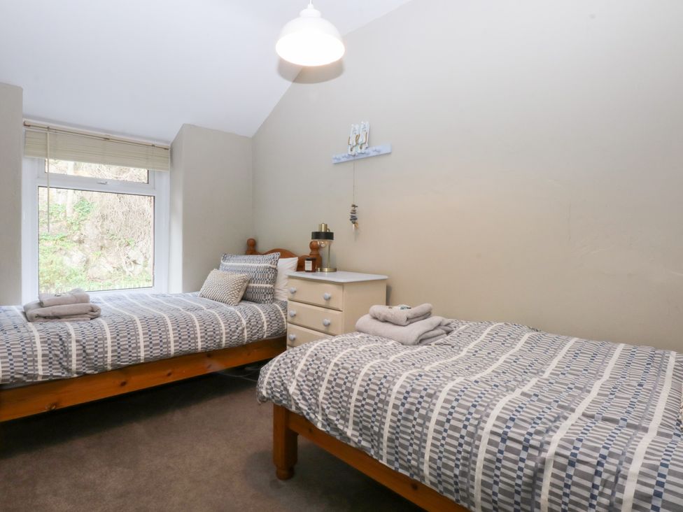 A bedroom with two beds and a bedside table at 3 Bay View Terrace in Llandegfan