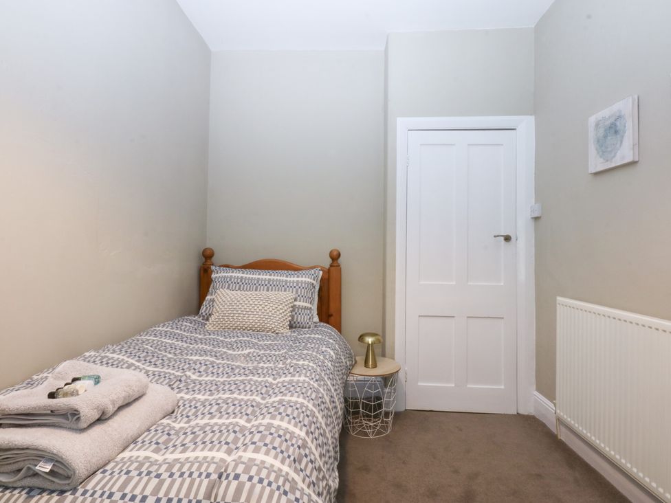 A bedroom with a single bed and a door at 3 Bay View Terrace in Llandegfan