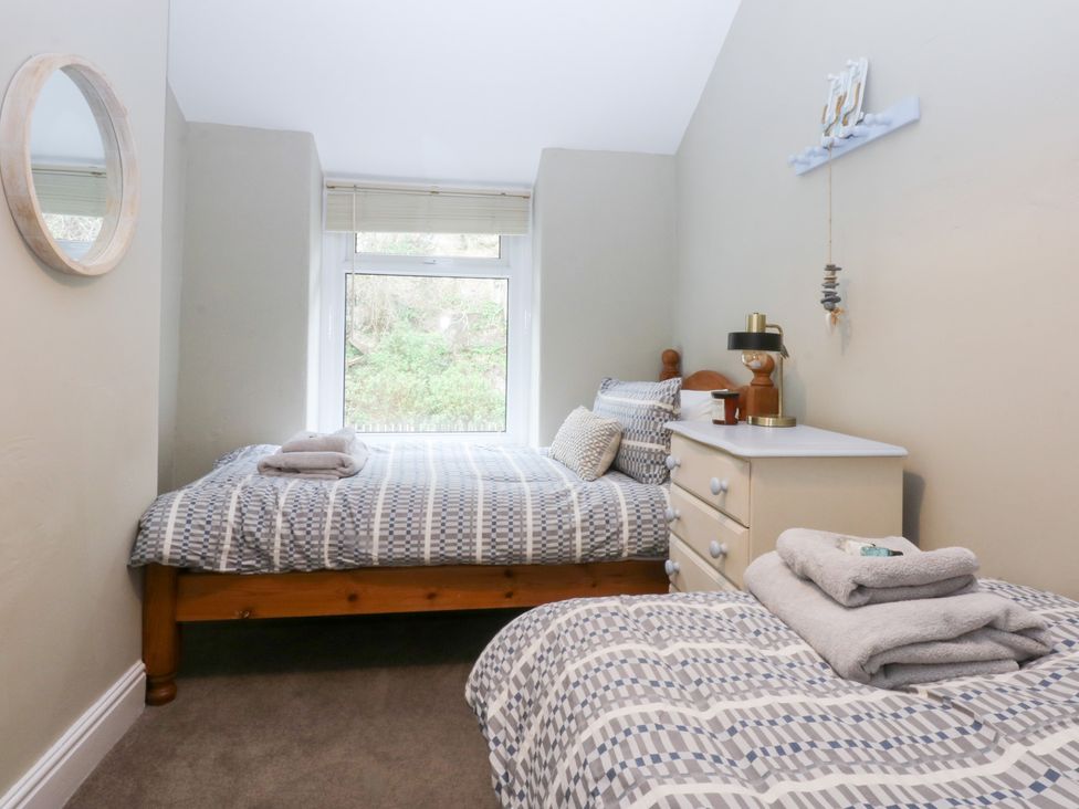 A bedroom with beds, a mirror, and a dresser at 3 Bay View Terrace, Llandegfan