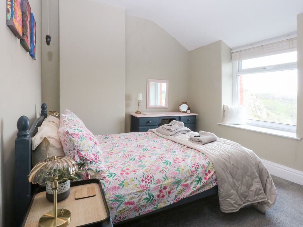 A bedroom with a bed and nightstand at 3 Bay View Terrace in Llandegfan
