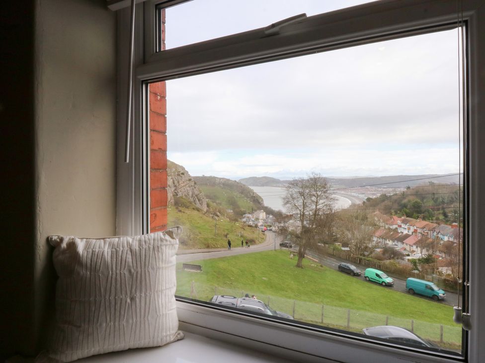 A window with a cushion overlooking a hill and road at 3 Bay View Terrace in Llandegfan