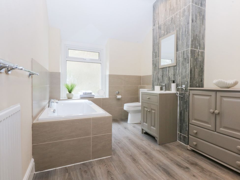 A bathroom with a bathtub, toilet, sink, and cabinet at 3 Bay View Terrace in Llandegfan