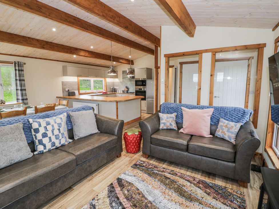 A living room with sofas and a kitchen area at Willow Lodge in Admaston near Abbots Bromley