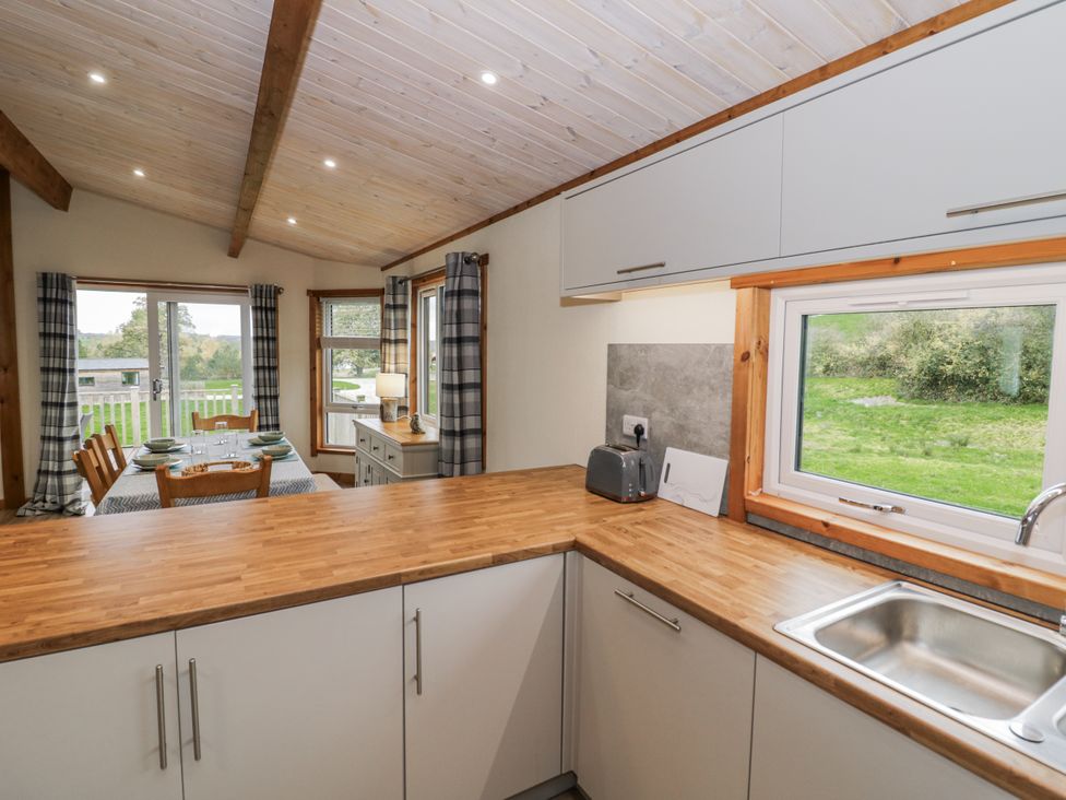 A kitchen with a sink and a dining table at Willow Lodge Admaston near Abbots Bromley