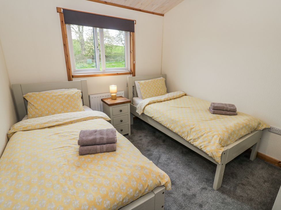 A bedroom with two beds and a bedside table at Willow Lodge in Admaston near Abbots Bromley