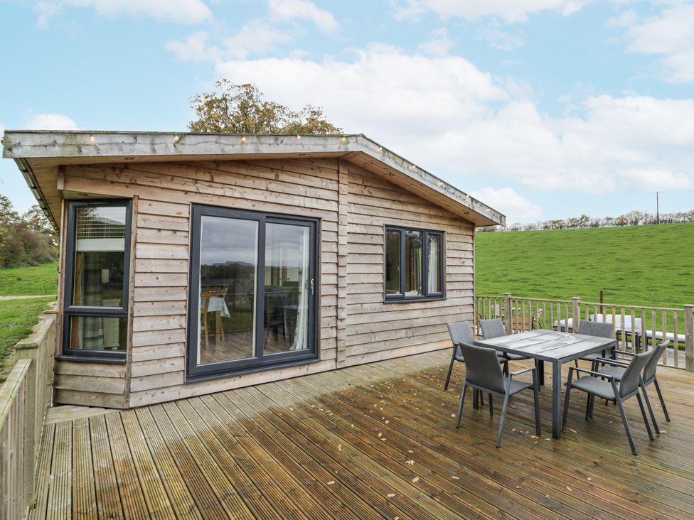 A wooden cabin with outdoor seating at Willow Lodge in Admaston near Abbots Bromley