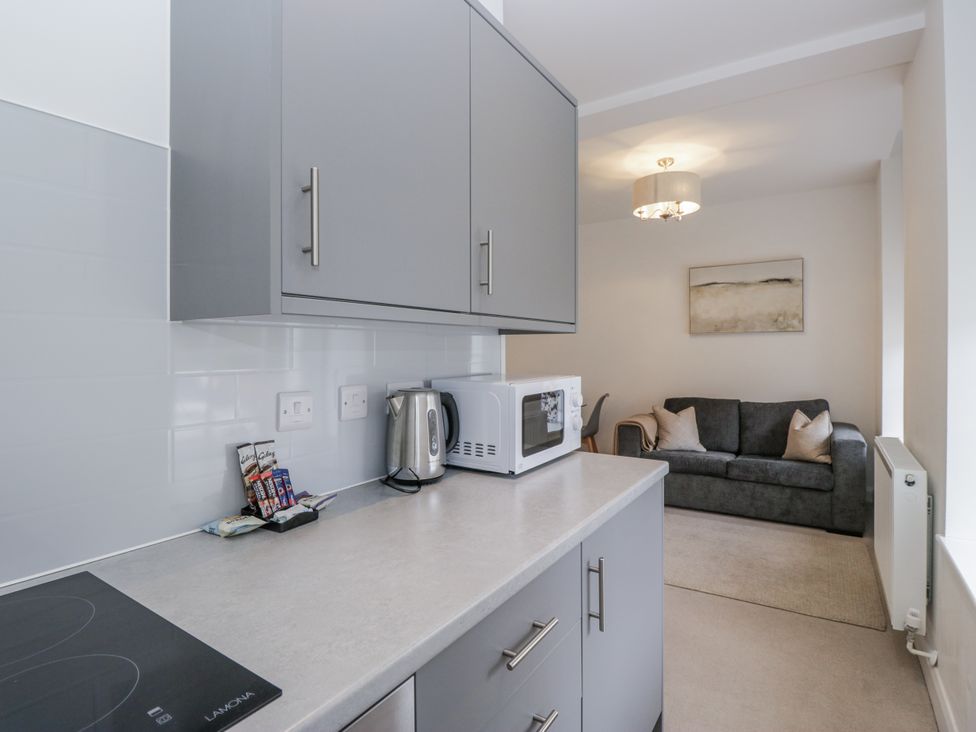 A kitchen with cabinets, a microwave, and a sofa at Derwent in Ulverston