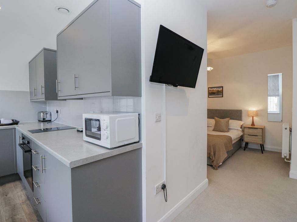A kitchen with appliances and a view of the bedroom at Derwent in Ulverston