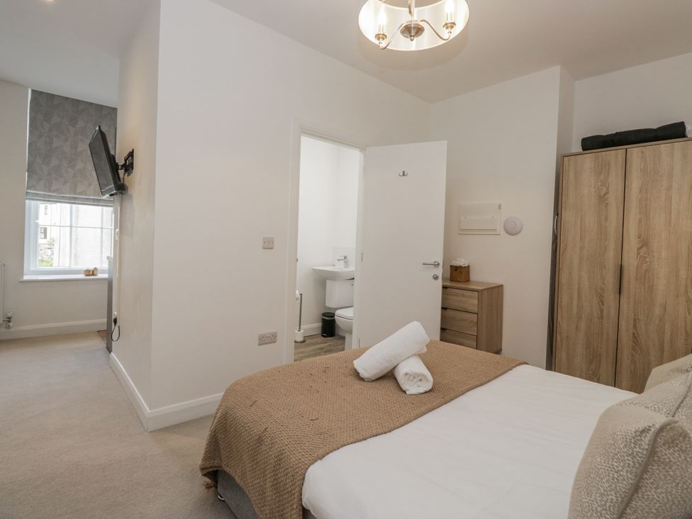 A bedroom with a bed and a bathroom door at Derwent in Ulverston
