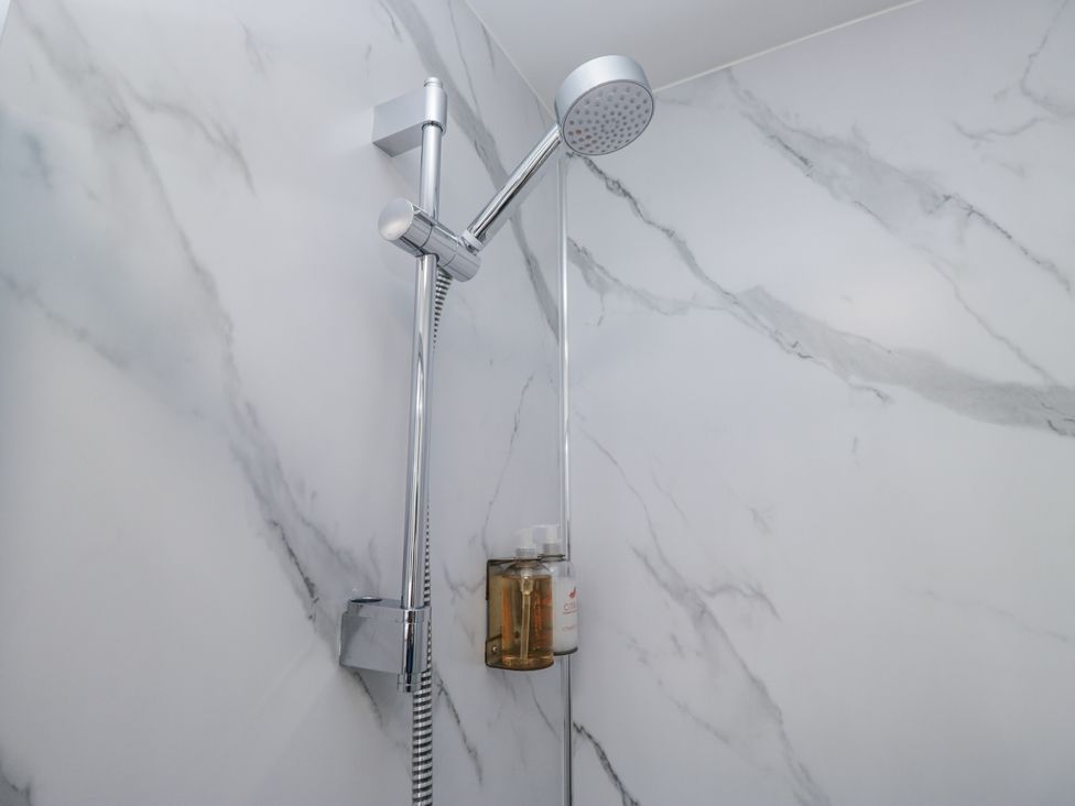 A shower area with a showerhead and soap dispenser at Derwent in Ulverston