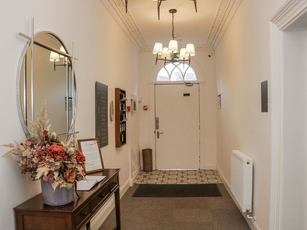 A hallway with a mirror and a flower arrangement at Derwent in Ulverston