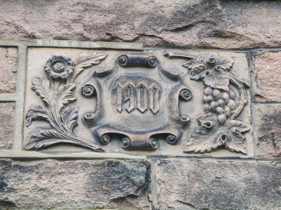 A stone carving with floral and grapevine designs featuring the year 1900 at Dorset Villas Matlock