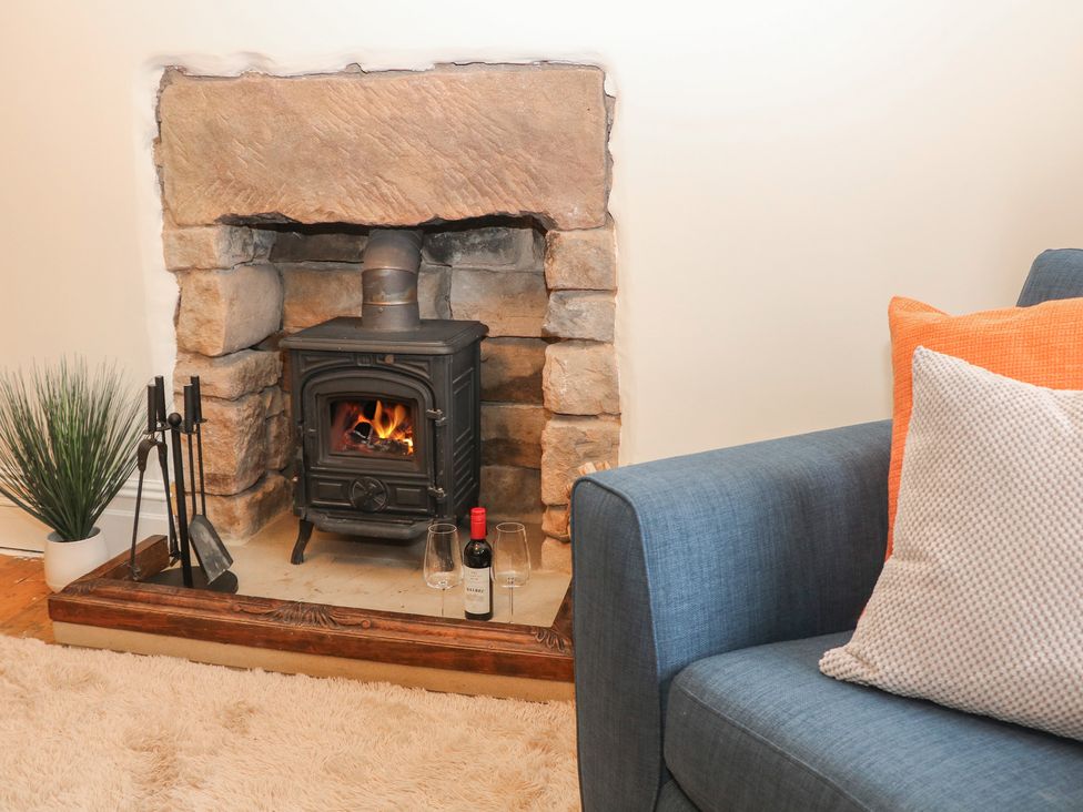A living room with a wood stove and wine bottle at Dorset Villas in Matlock