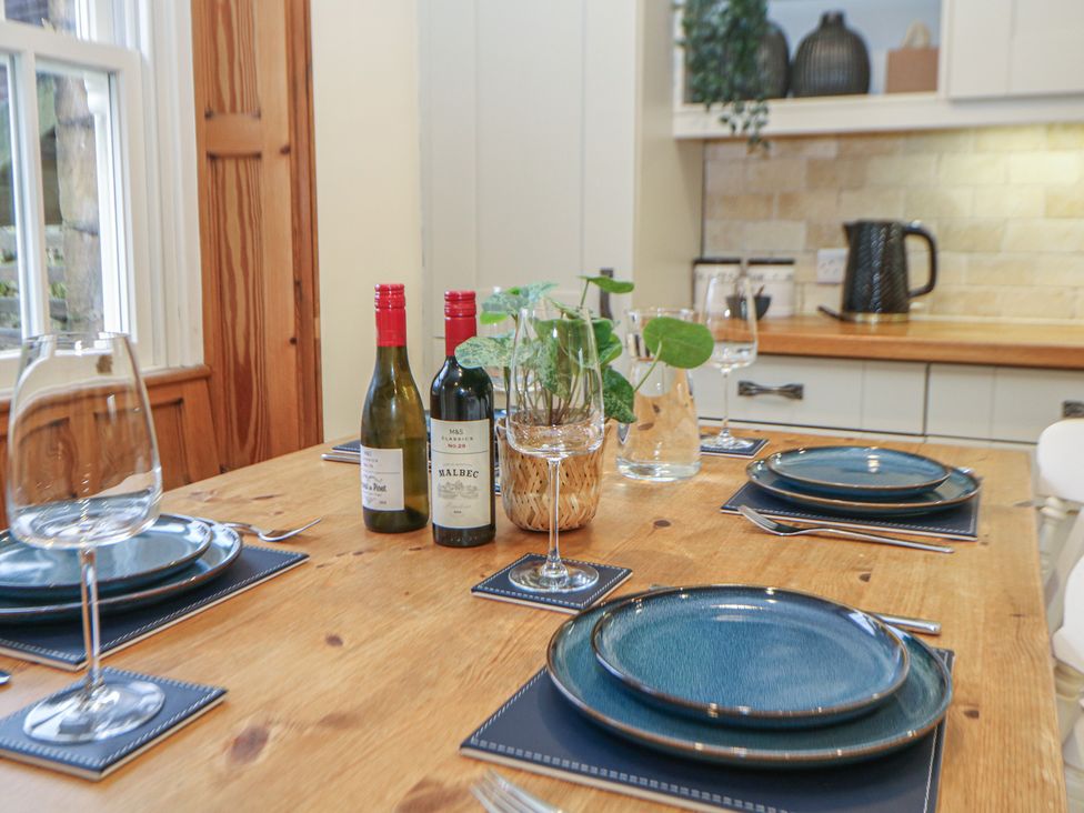 A dining room with wine bottles and plates on the table at Dorset Villas Matlock