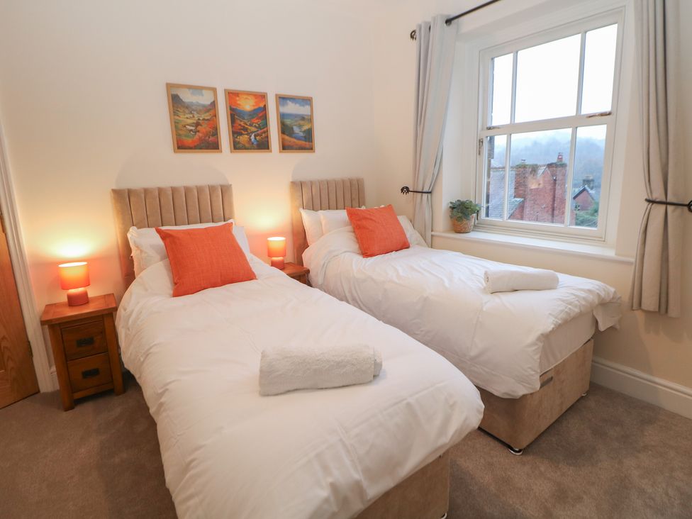 A bedroom with two beds and paintings on the wall at Dorset Villas in Matlock