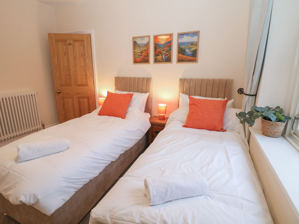 A bedroom with two single beds and a decorative wall at Dorset Villas in Matlock