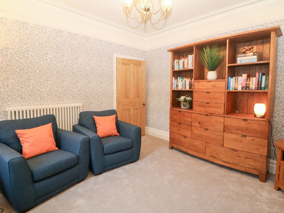 A living room with a sofa and a bookshelf at Dorset Villas in Matlock