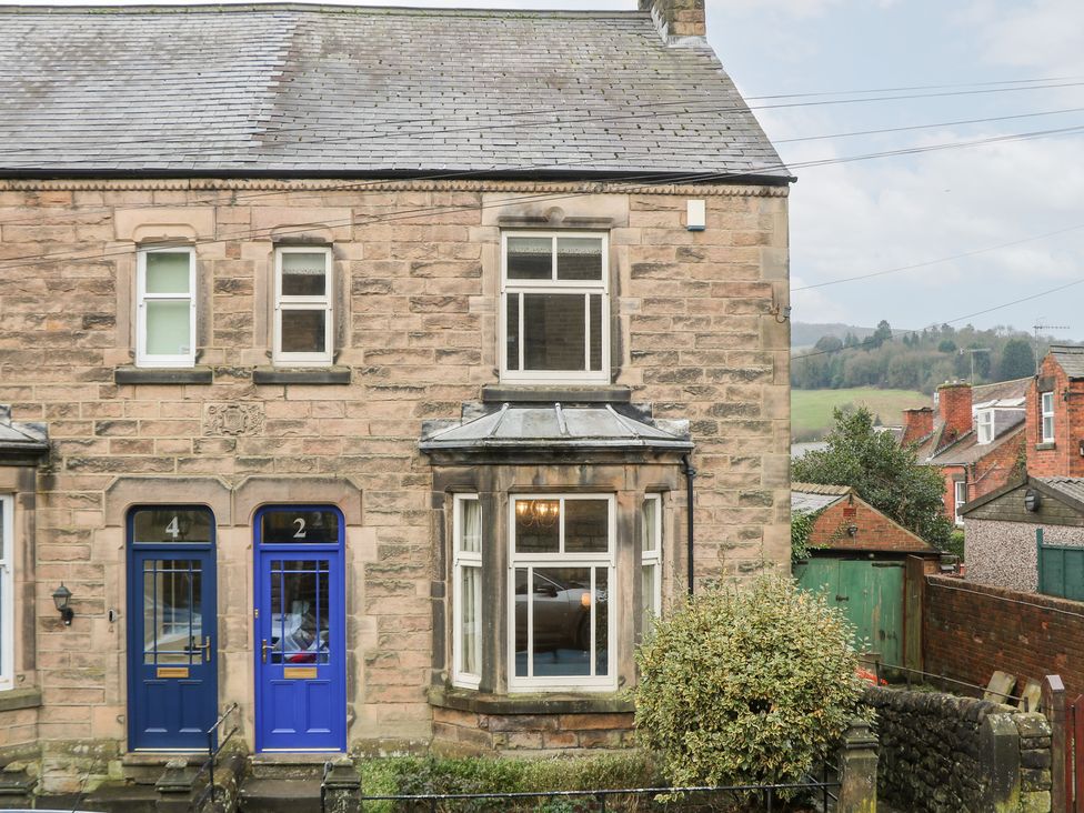 A stone building with blue front doors and windows at Dorset Villas in Matlock