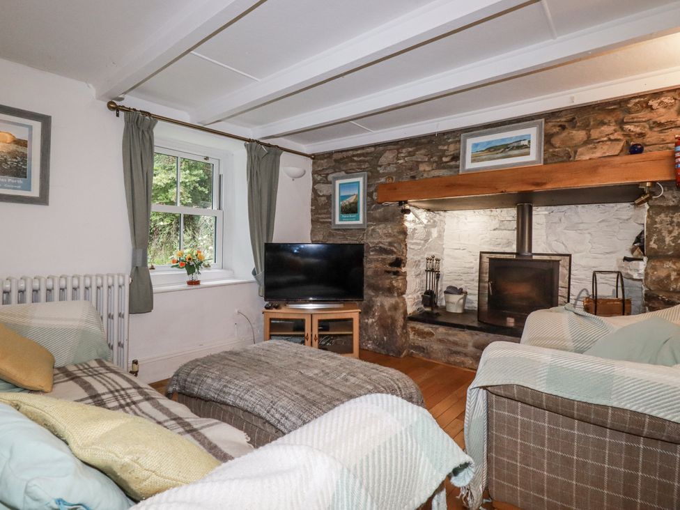 A living room with a television and a fireplace at Blowing House Cottage in Perranporth
