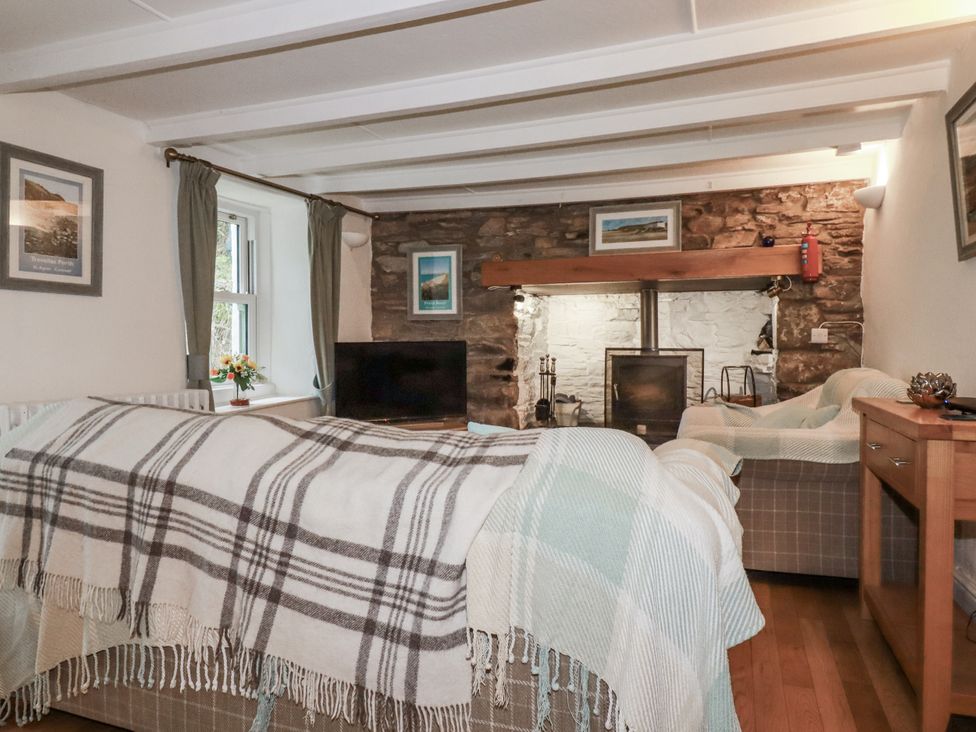 A living room with a sofa and television at Blowing House Cottage in Perranporth