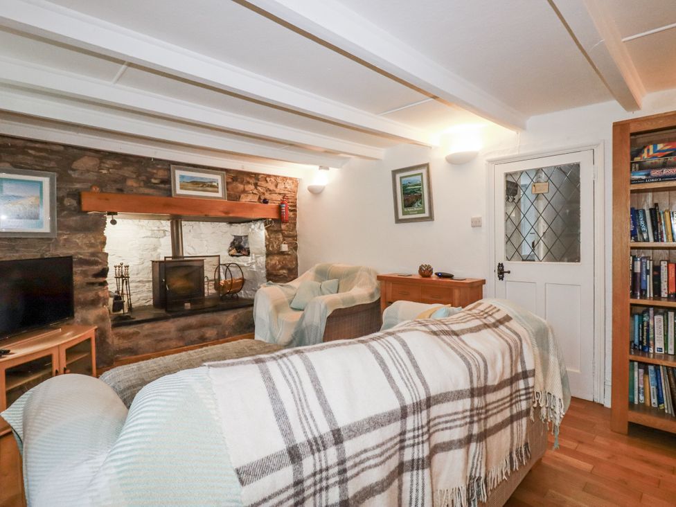 A living room with a sofa and television at Blowing House Cottage in Perranporth