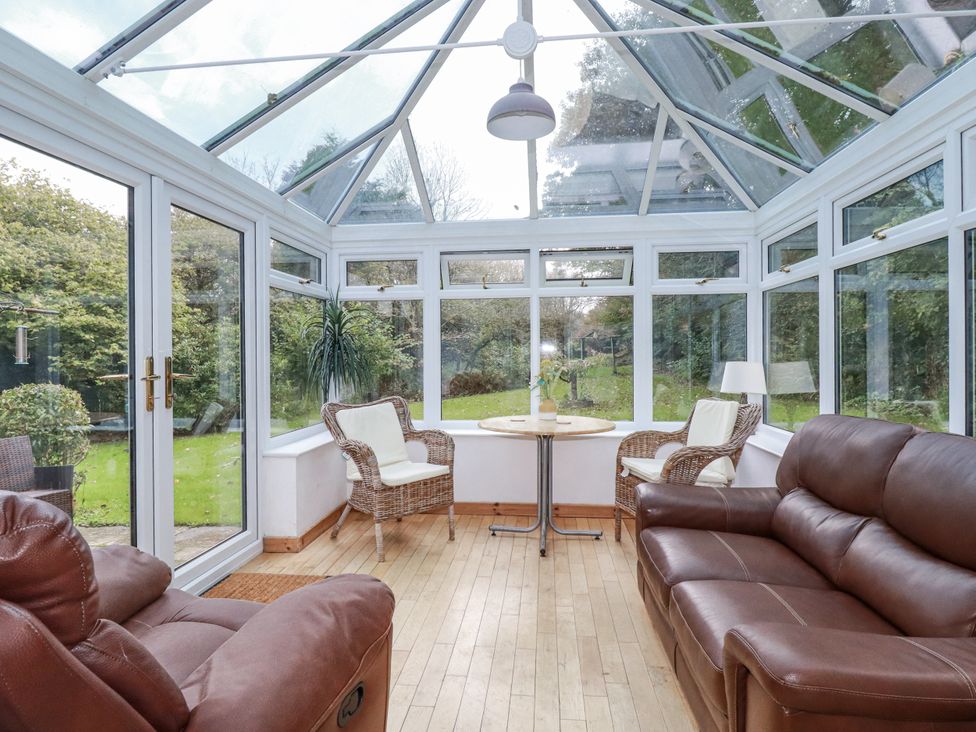 A conservatory with seating and a table at Blowing House Cottage Perranporth