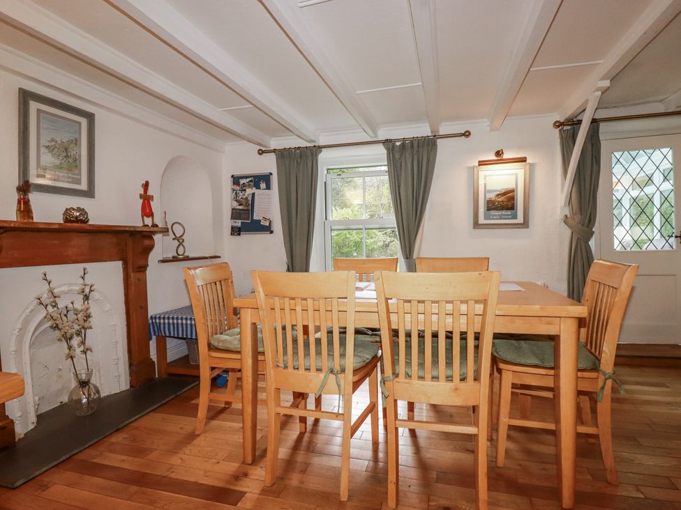 A dining room with a wooden table and chairs at Blowing House Cottage Perranporth
