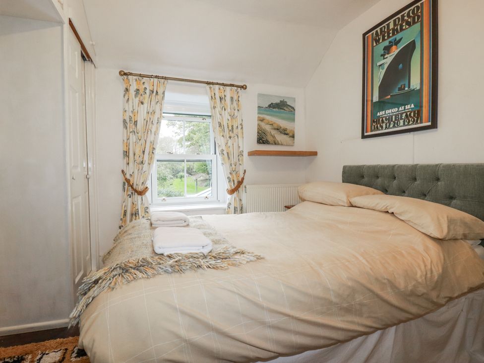 A bedroom with a bed and window at Blowing House Cottage in Perranporth