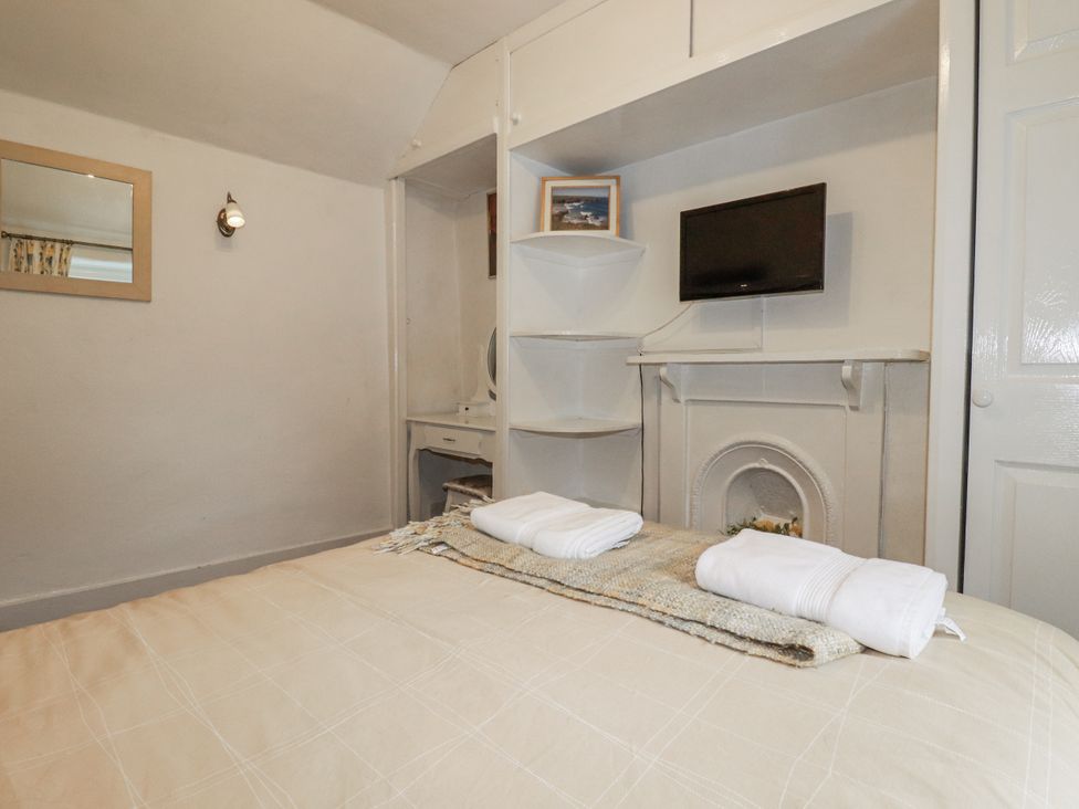 A bedroom with a bed and TV at Blowing House Cottage in Perranporth