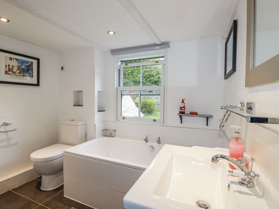 A bathroom with a bath tub, toilet, and sink at Blowing House Cottage Perranporth