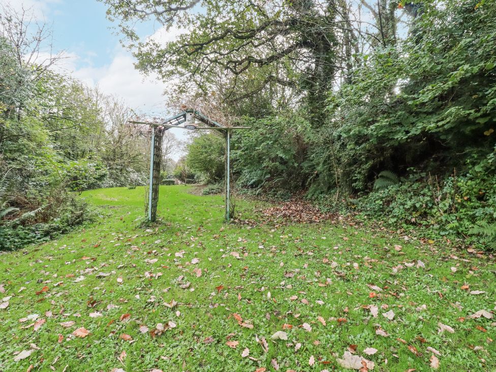 A garden with an archway and fallen leaves at Blowing House Cottage Perranporth