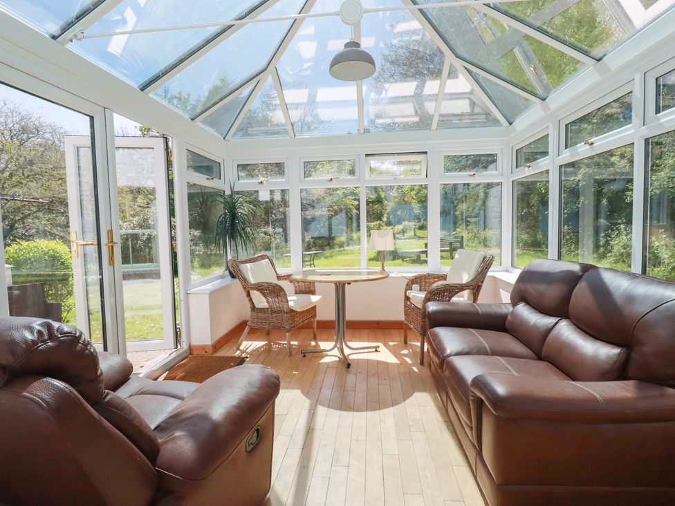 A conservatory with sofas and tables at Blowing House Cottage near Perranporth