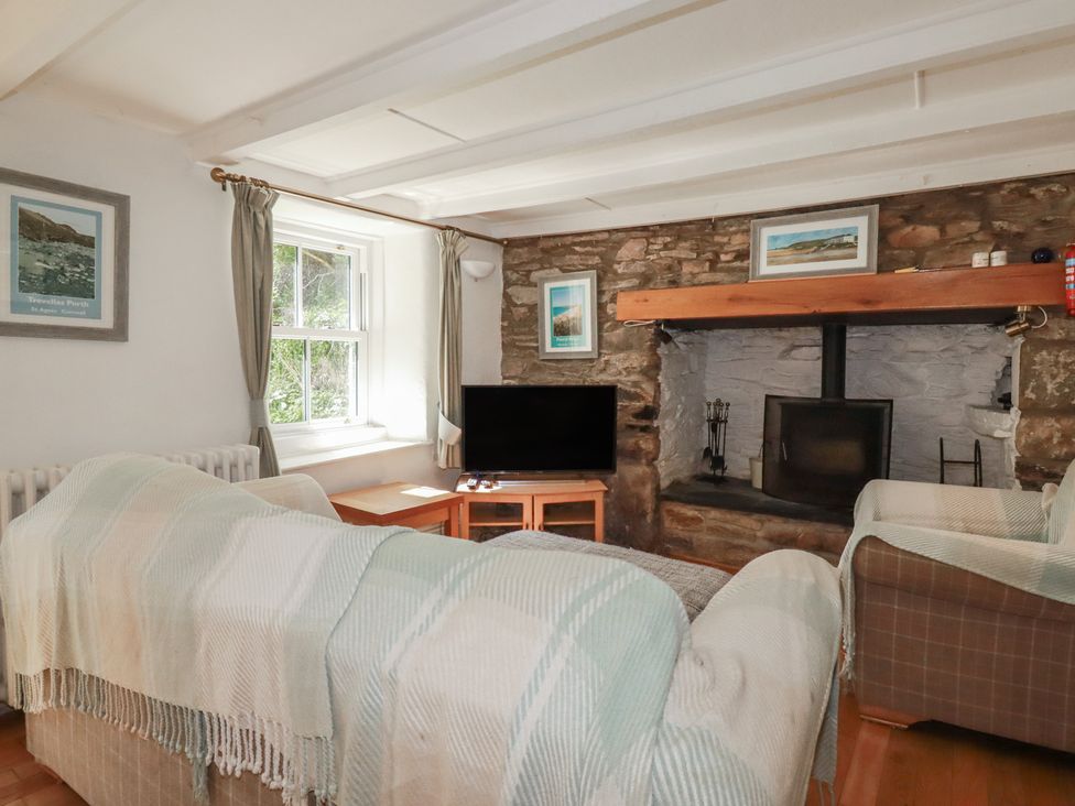 A living room with a fireplace and television at Blowing House Cottage near Perranporth
