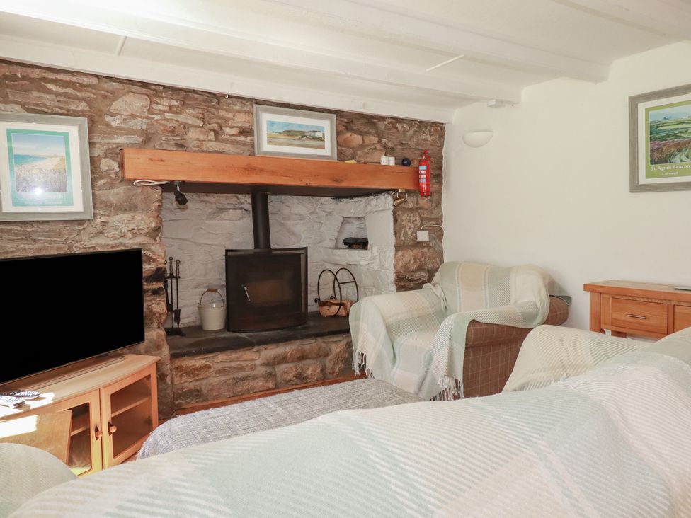 A living room with a fireplace and television at Blowing House Cottage near Perranporth