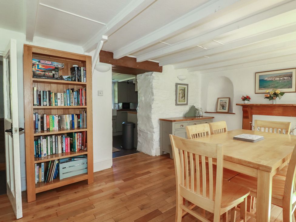 A dining room with a bookshelf and a dining table at Blowing House Cottage near Perranporth