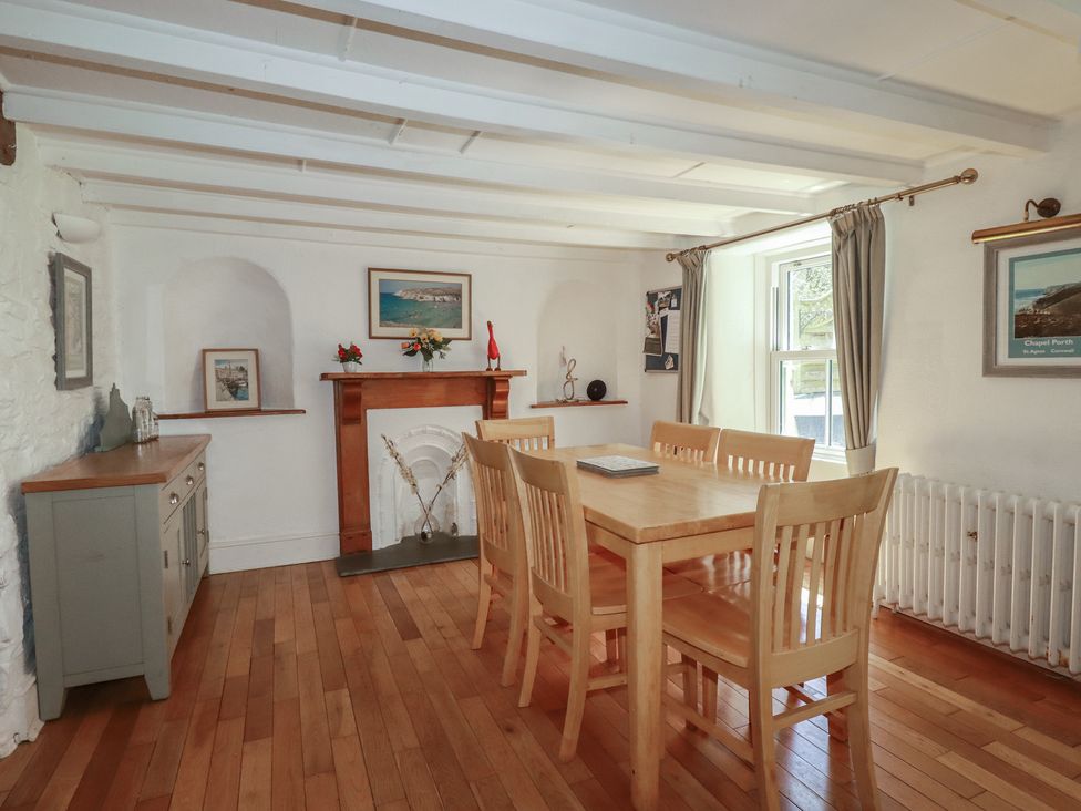 A dining room with a wooden table and chairs at Blowing House Cottage near Perranporth