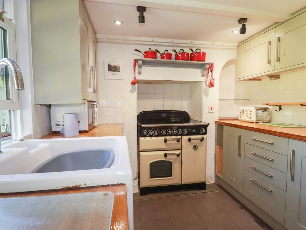 A kitchen with a cooker and microwave at Blowing House Cottage near Perranporth