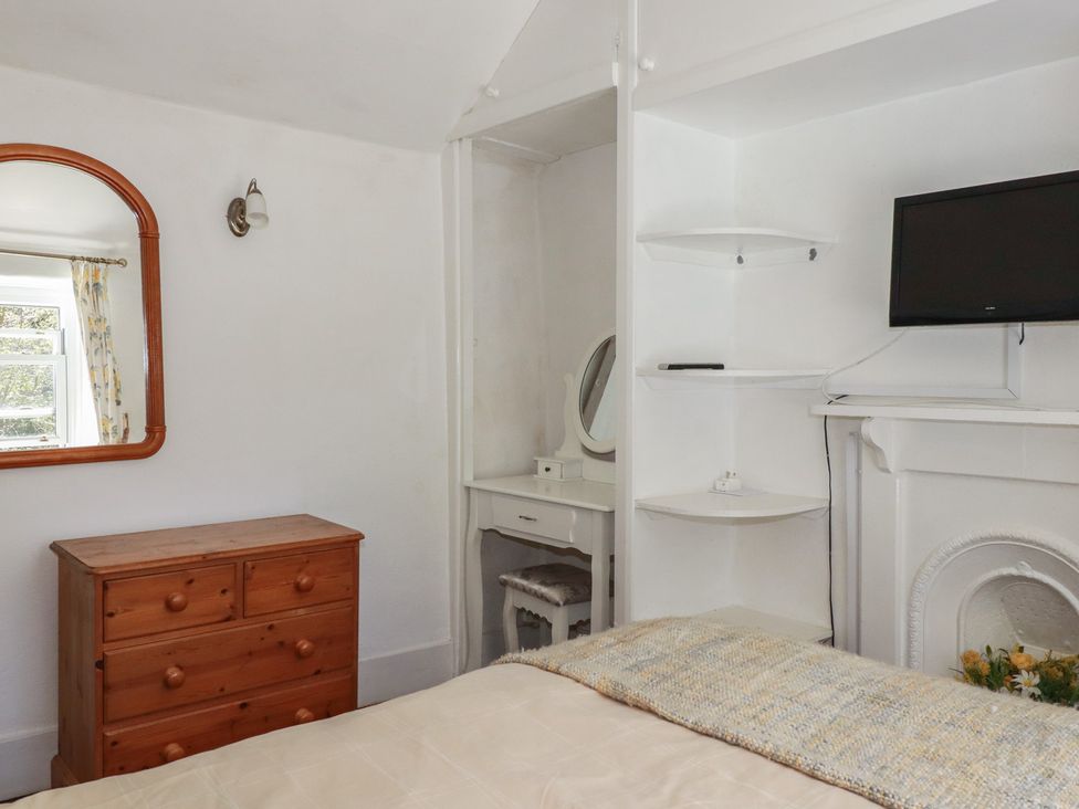 A bedroom with a mirror and chest of drawers at Blowing House Cottage near Perranporth