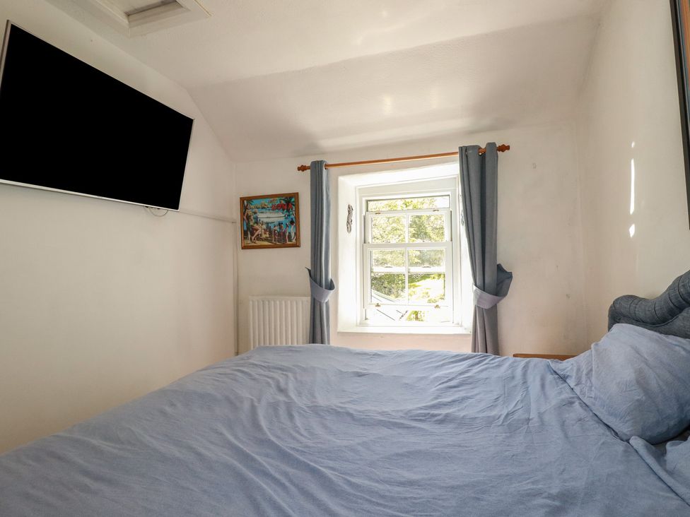 A bedroom with a bed and a television at Blowing House Cottage near Perranporth