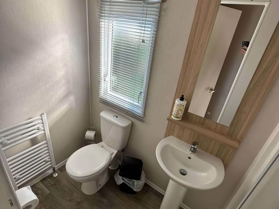 A bathroom with a toilet, sink, and window