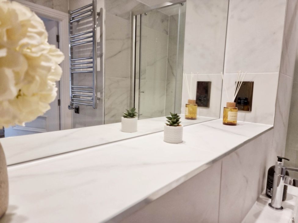 A bathroom with a mirror, shelf, and decorative items at 