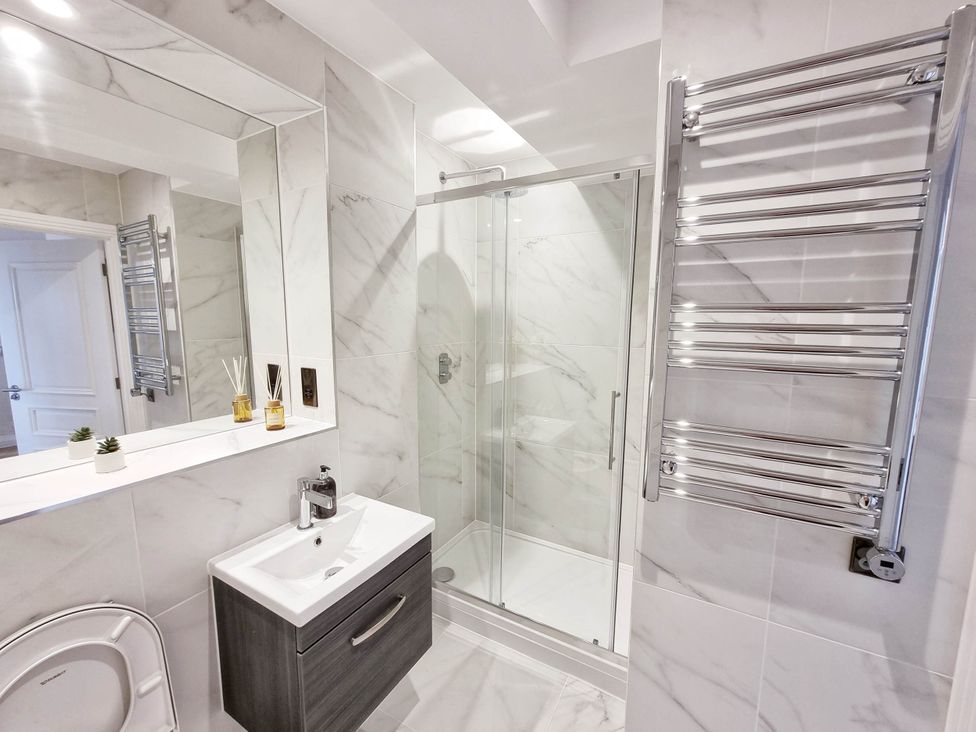 A bathroom with a shower, sink, towel rail, and toilet