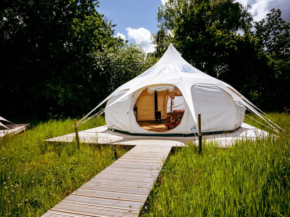 A tent with a wooden deck and pathway in a grassy area