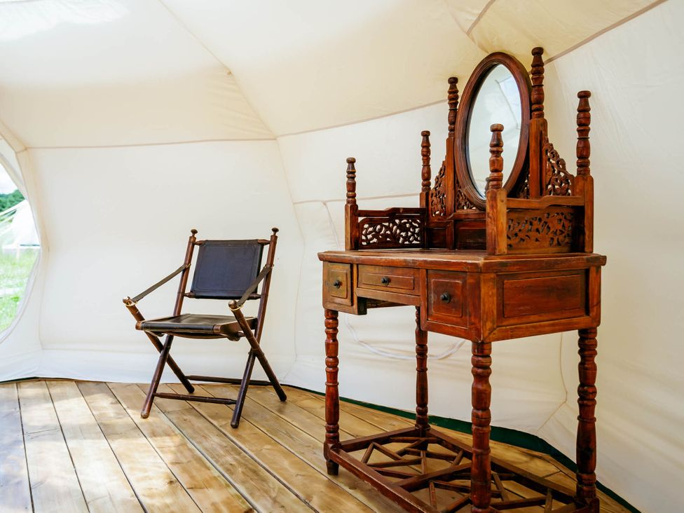 A wooden chair and a vanity with a mirror in a tent interior