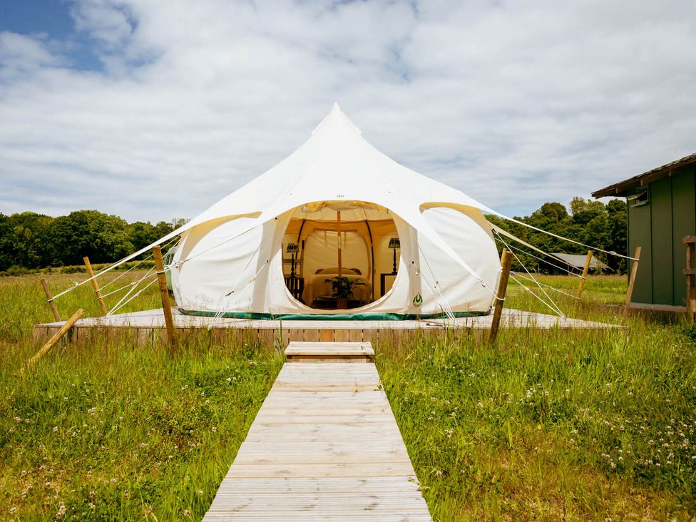 A tent with a wooden pathway in a grassy area